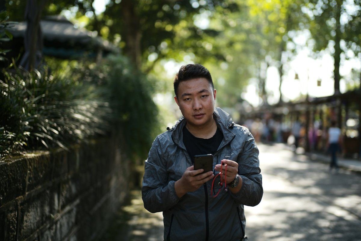 一名男子在林荫小路上看手机