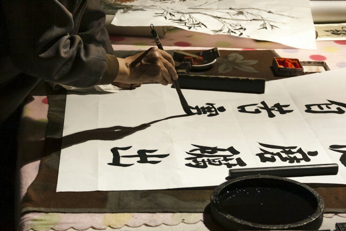 一只手执毛笔,在白纸上书写大字
